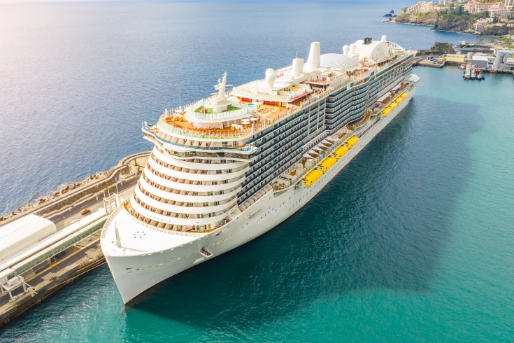 Travel insurance cruise banner of a ship docked on bright ocean water.
